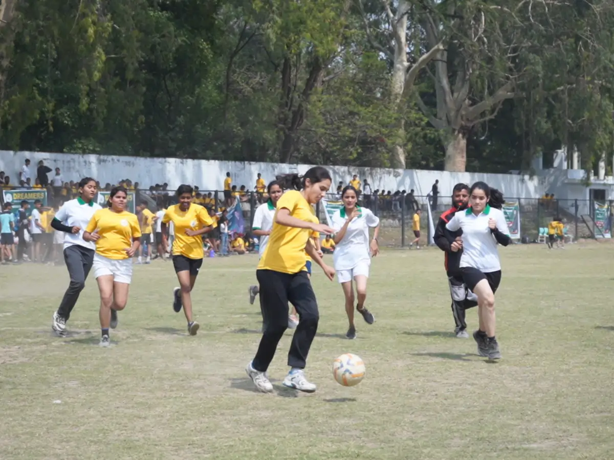 Best NDA Coaching Institute in Dehradun — Syllabus, Fees, Batches Students playing a football match on an outdoor ground while others watch from the sidelines.
