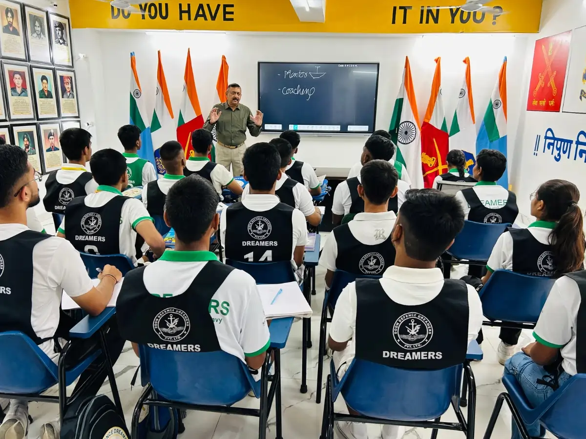 Best NDA Coaching Institute in Dehradun — Syllabus, Fees, Batches Instructor teaching a class in front of a smart board with Indian flags displayed around the room.