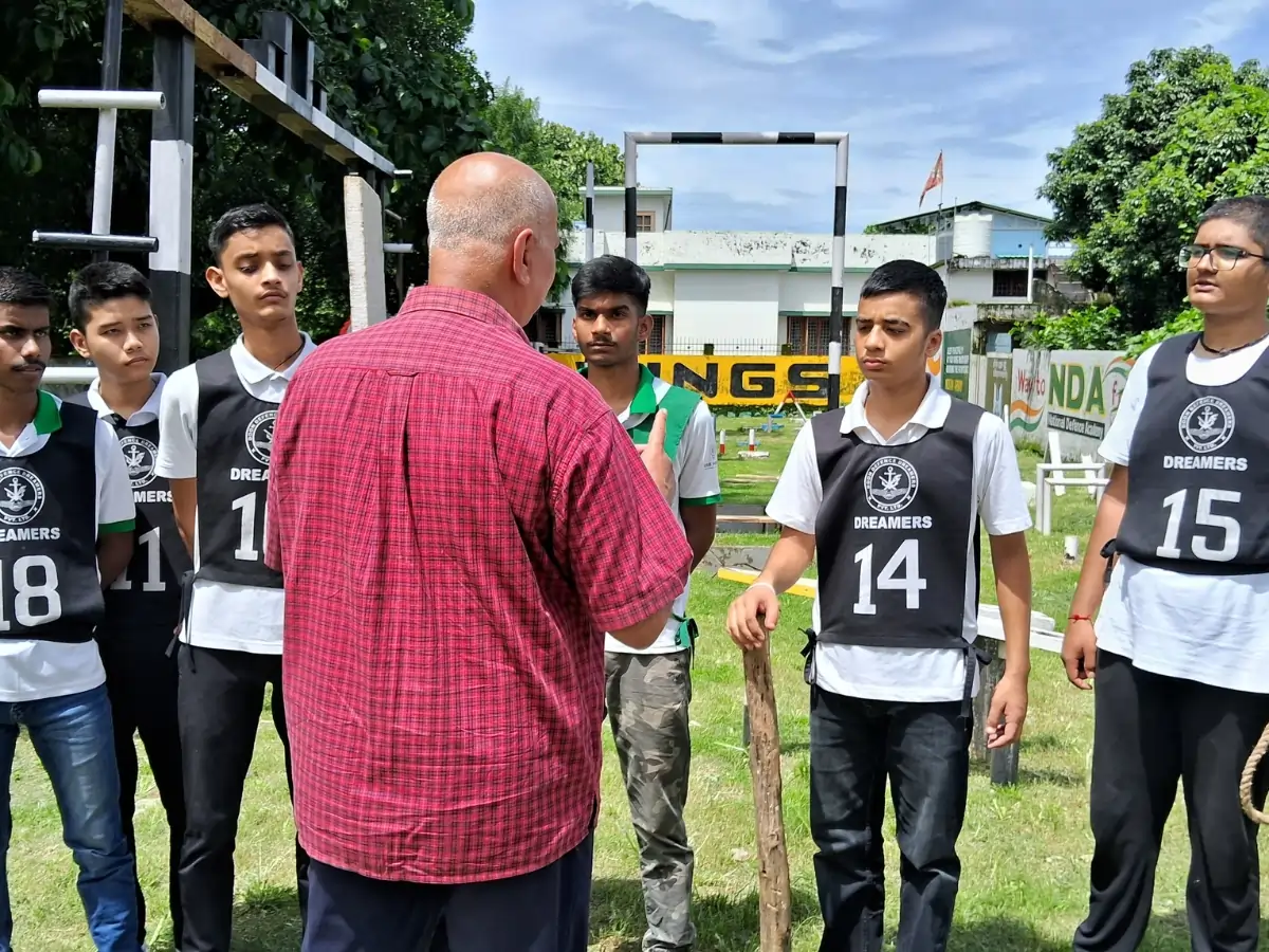 Best NDA Coaching Institute in Dehradun — Syllabus, Fees, Batches Instructor addressing a group of students wearing training bibs during an outdoor session.