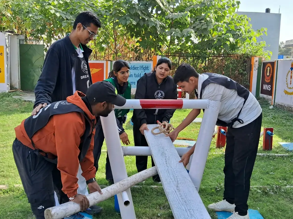 Best NDA Coaching Institute in Dehradun — Syllabus, Fees, Batches Students working together on an outdoor obstacle task using wooden planks and ropes.