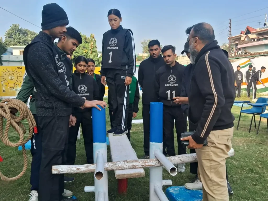 Students performing a balance and coordination task on training equipment while an instructor guides them.